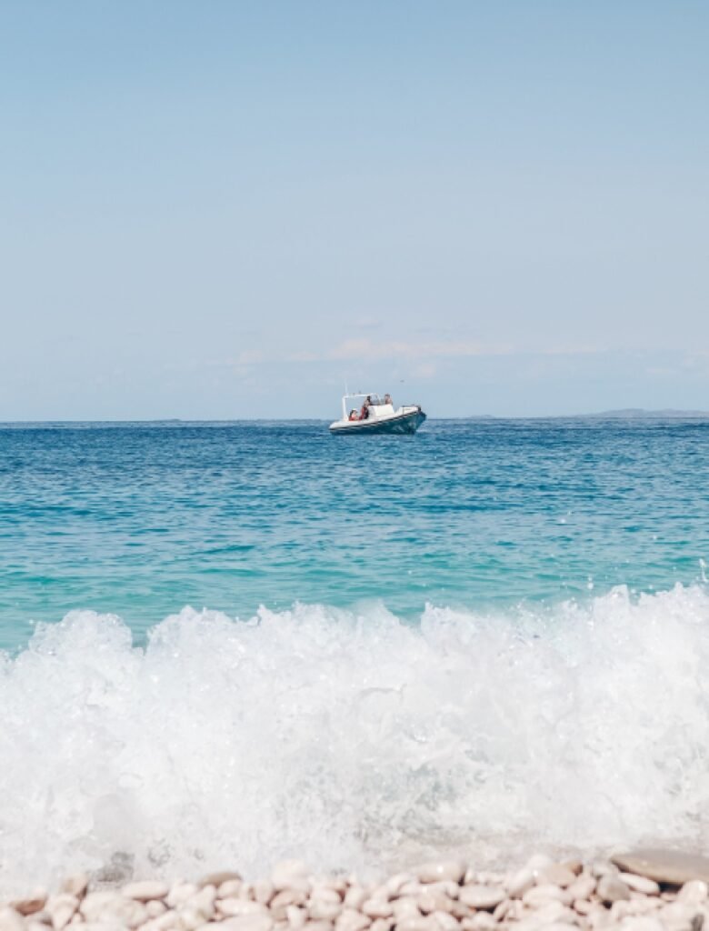 A boat sails across the waters of Karaburun Peninsula beaches, Vlore, with people enjoying a trip.